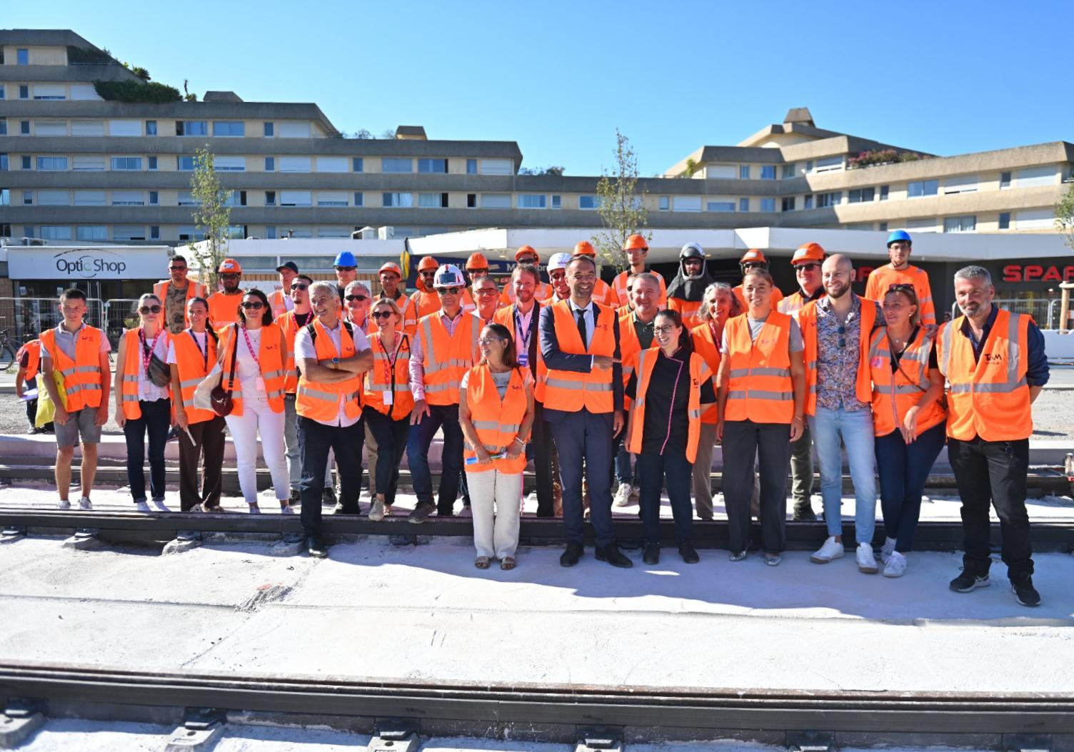 photo de groupe avec élus, habitants et commerçants du quartier, ouvrier et personnels de la TaM, grande résidence en arrière plan 