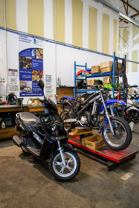 véhicules deux roues dans l'atelier du garage solidaire étagères outils affiches