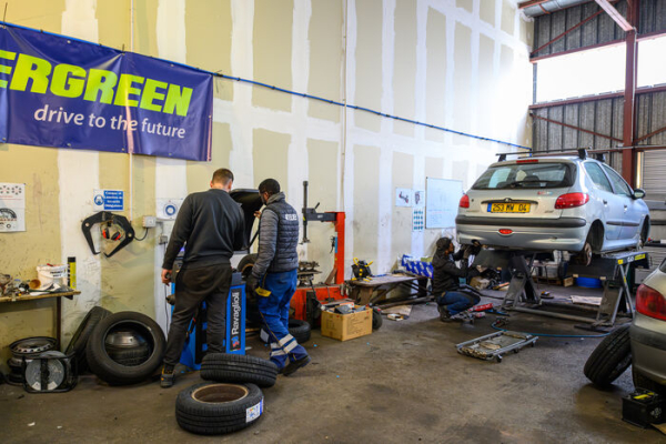voiture surélevée, outils, ouvriers, pneus dans le garage solidaire